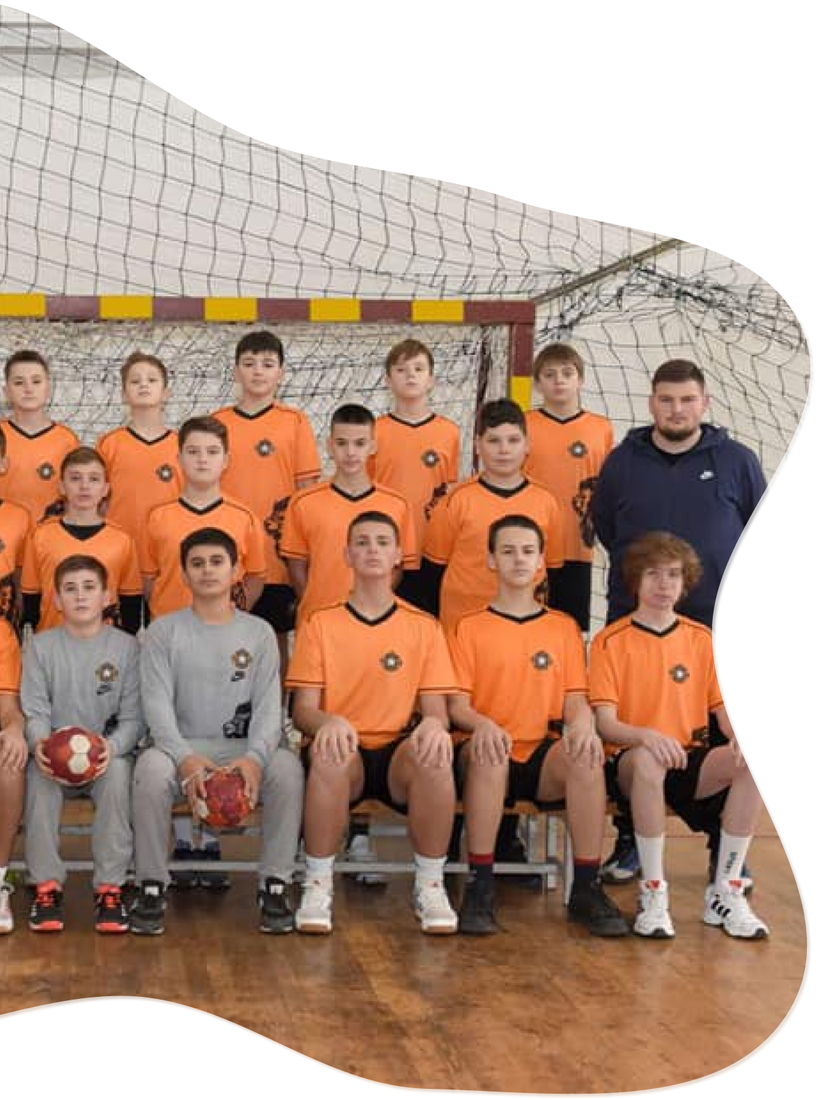 Young academy team in orange clothing and 2 boys dressed in grey clothing